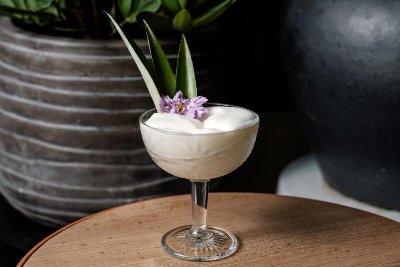 glass of Aba Austin's Pina Express with flower garnishes