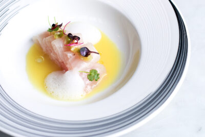 Miru Hamachi on a white plate sitting on a white marble table