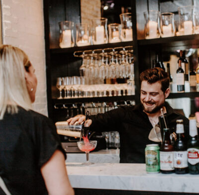 a bartender pours a cocktail for a customer