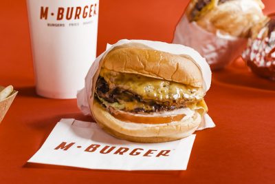 double cheeseburger sitting on an M Burger napkin on a red counter