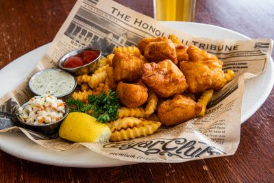 a plate of fried fish nuggets with french fries served on newspaper