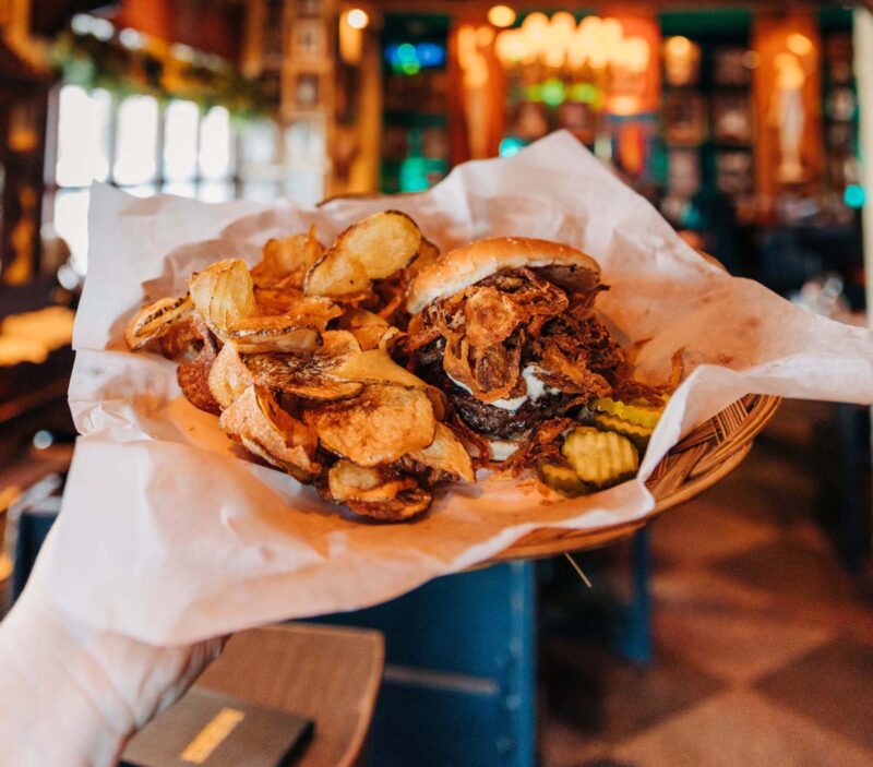 The signature Grunt burger with fried onions and blue cheese. House made potato chips and pickle slices