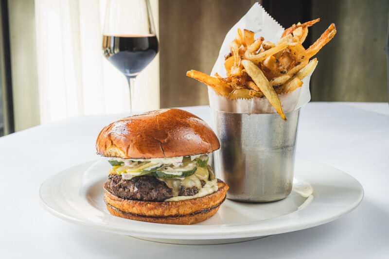 A cheeseburger with fries and a glass of red wine.