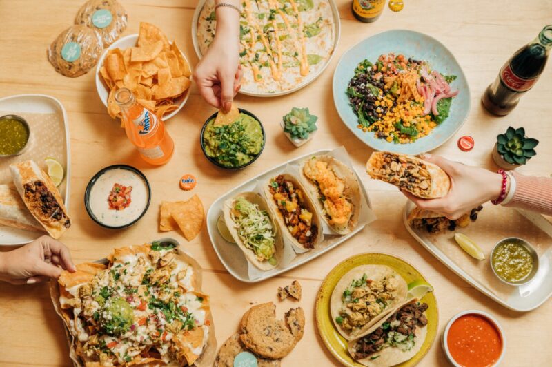 overhead shot of tacos next to different salads and side dishes