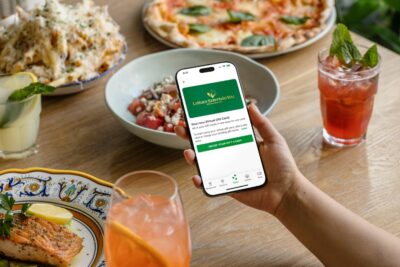 Hand holding a smart phone showing LettuceEats App Merge Balance and Virtual Gift Card feature