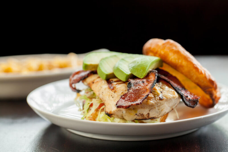 Hearty Wildfire's gluten free chicken club sandwich on a plate, made with bacon and avocado slices