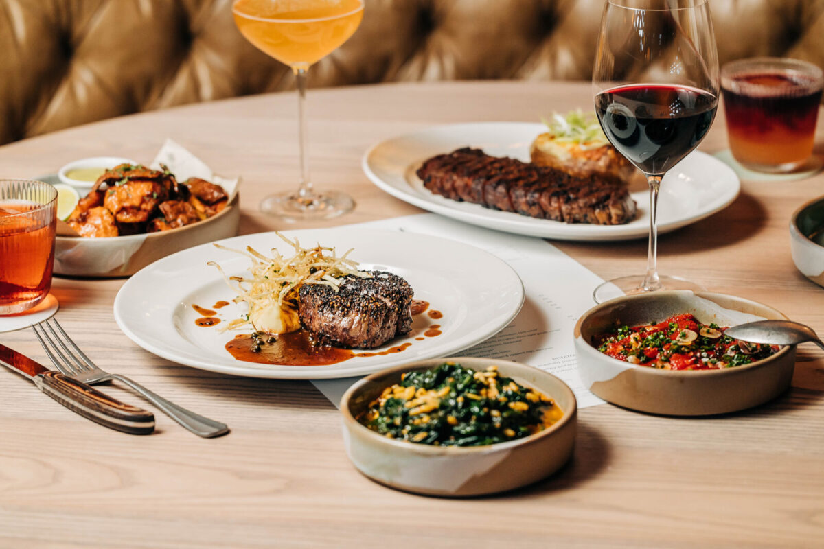 Filet Mignon and Strip Steak with various side dishes and speciality cocktails on a table