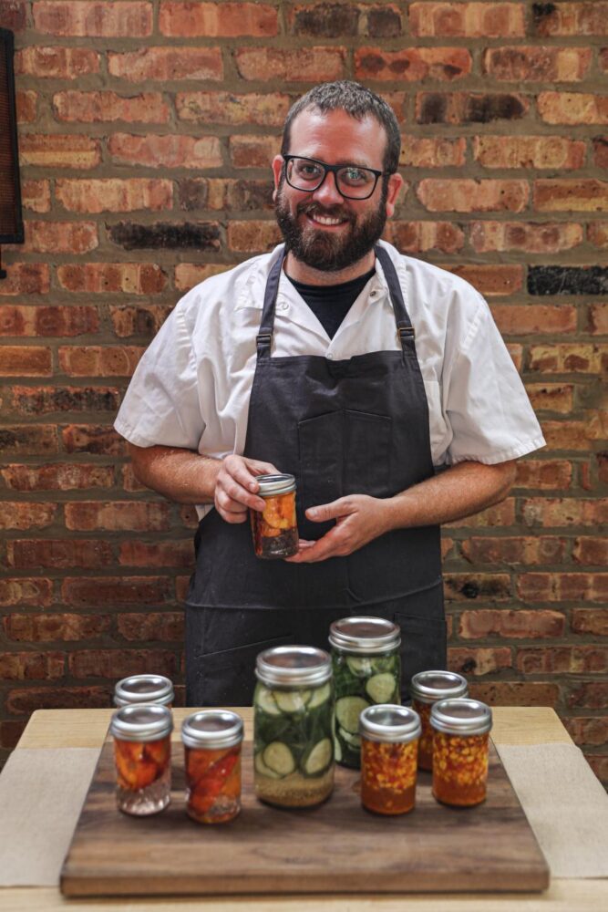 Chef Ben Goodnick holding a can pickles during a demo at Summer House