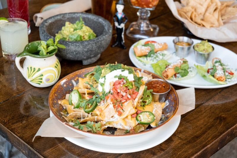 Spread of popular appetizers in cluding nachos, taquitos, and fresh-made guacamole