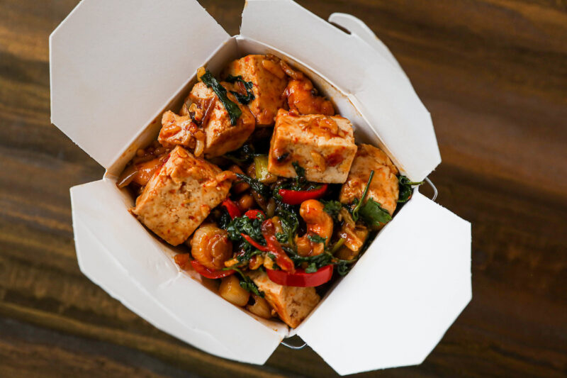 Takeout container packed with a tofu and vegetables dish from Big Bowl