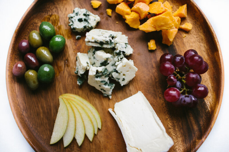 Cheese, fruits and olives on a board