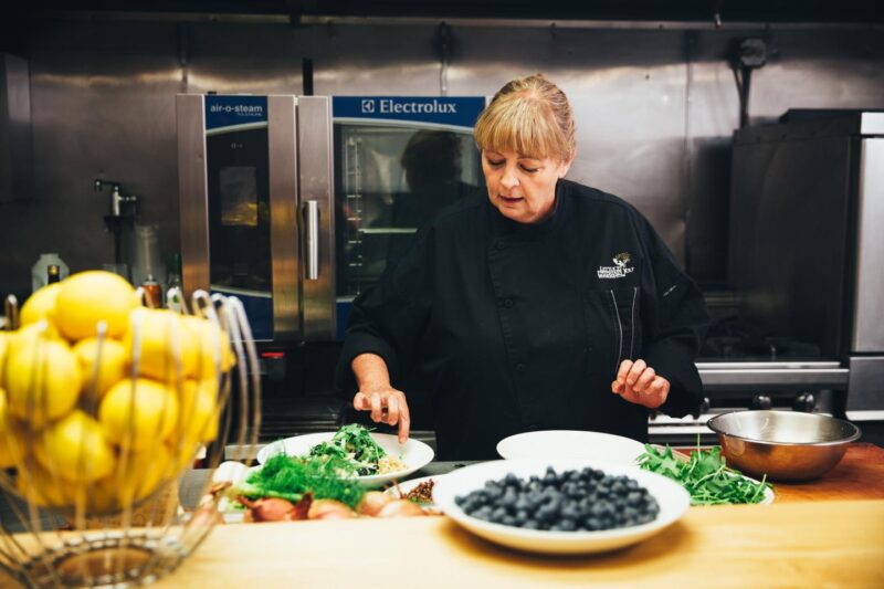 Chef Rita preparing a salad with arugula and blueberries