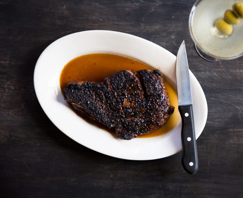 Bone-In Ribeye with a steak knife sitting on the edge of the plate