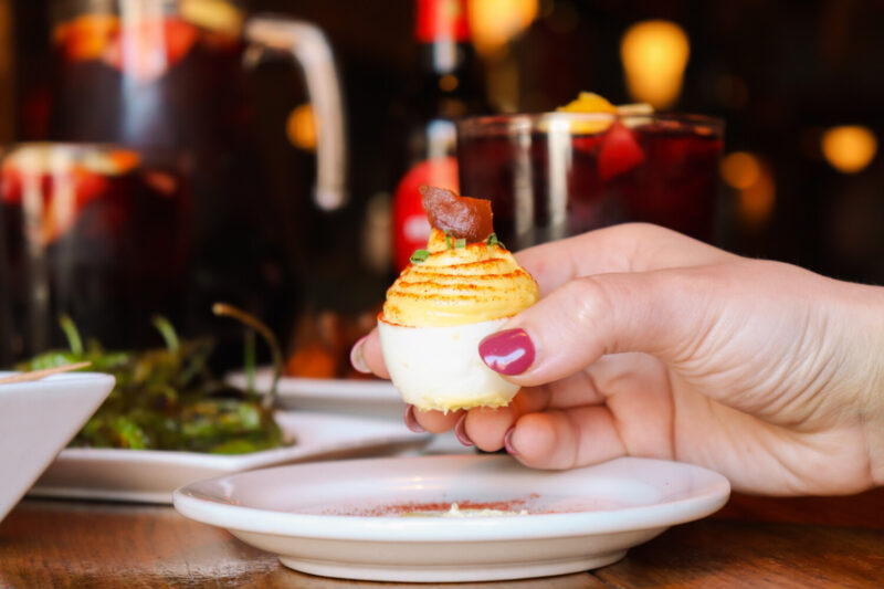 A women's hand holding a deviled egg.