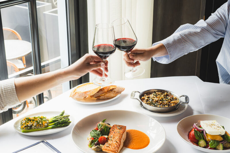 Two people enjoying red wine and food at Mon Ami Gabi