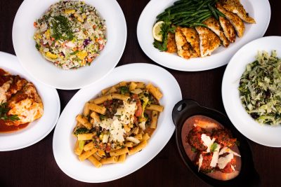 Overhead shot of a variety of menu offerings including rigatoni, chopped salads, chicken and meatballs