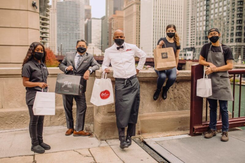 servers wearing masks with carryout bags 