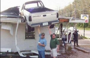 Photo souvenir devant une Chevrolet qui a atterri sur le toit d'une maison