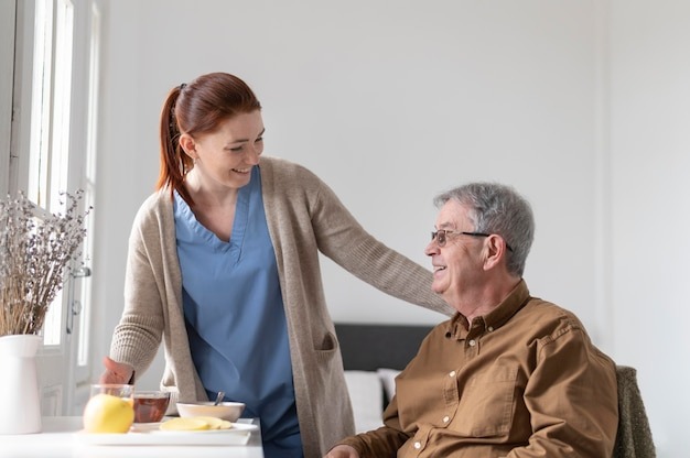 Nurse serving breakfast with a smile to a gentleman