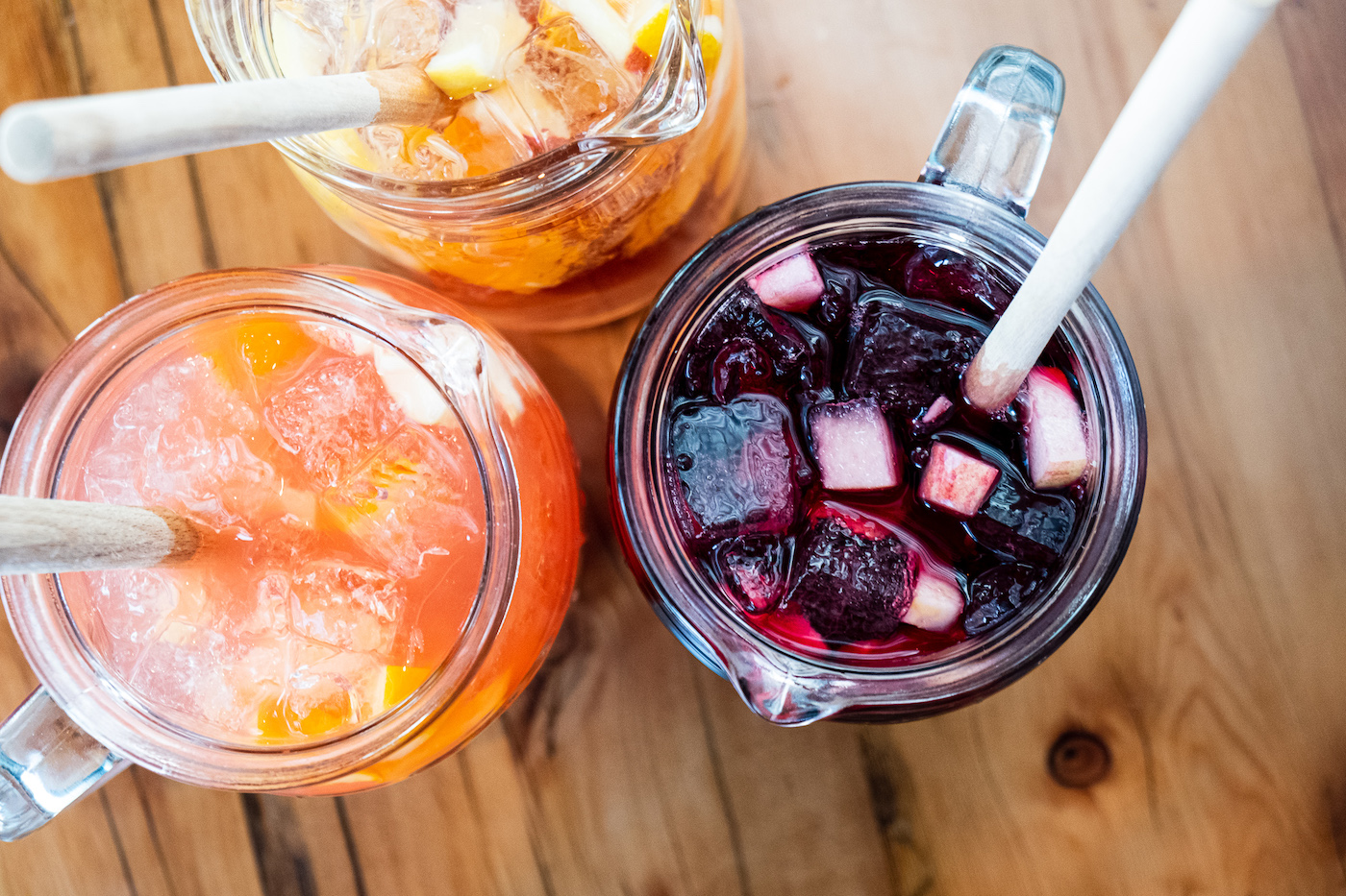 Pitchers of seasonal sangria with fruit on a wood table