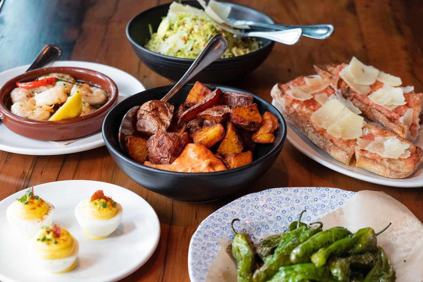 Spicy Potatoes, Deviled Eggs, Garlic Shrimp, and Catalan Bread on plates at Lil' Ba-Ba-Reeba in River North.