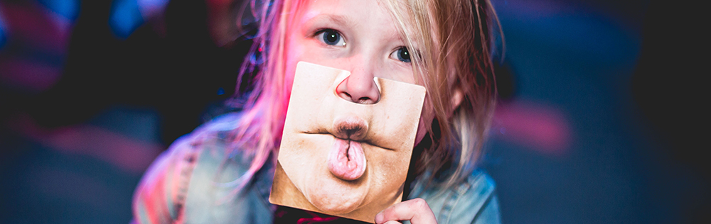 young child holding silly face mask 