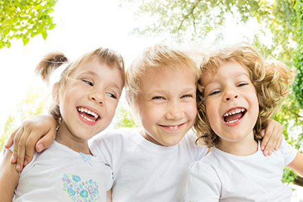 Three children smiling in the garden.