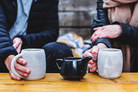 Couple drink a warm beverage together to keep warm during the winter.