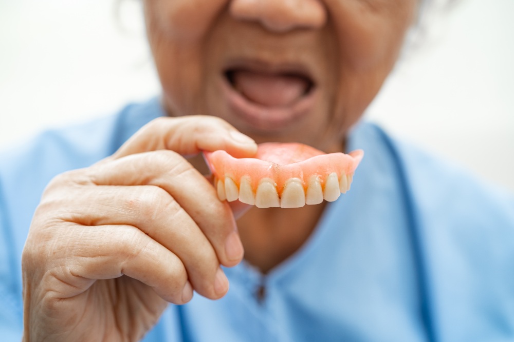 Woman putting false teeth into her mouth