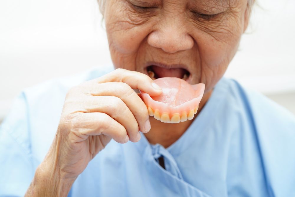 Woman inserting full upper denture in Tweed Heads