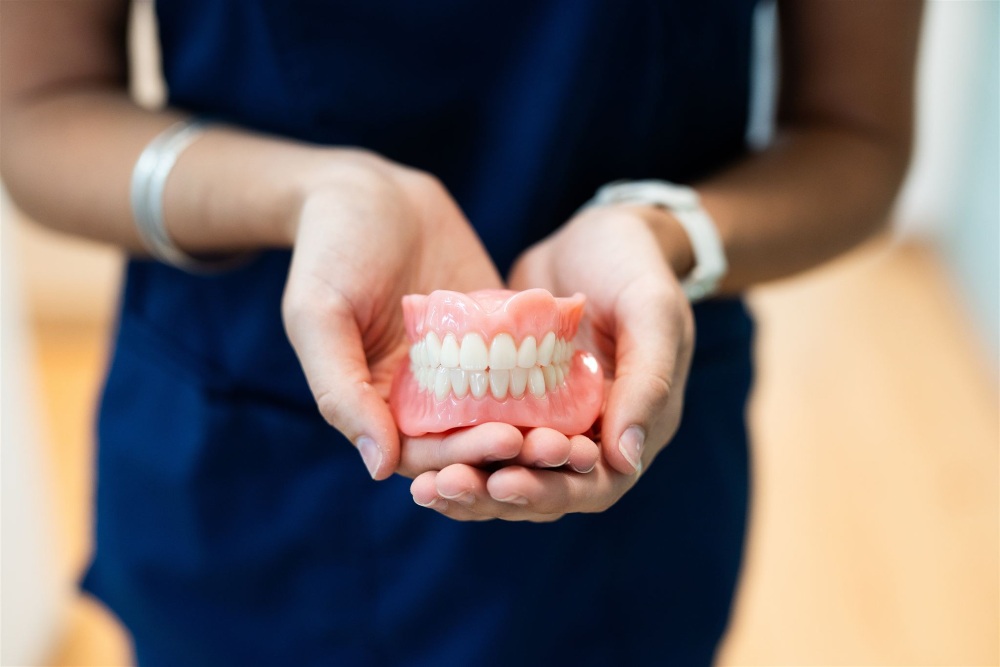 Dental prosthetist holding new dentures