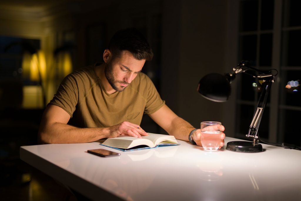 A men reading a book under the lamp