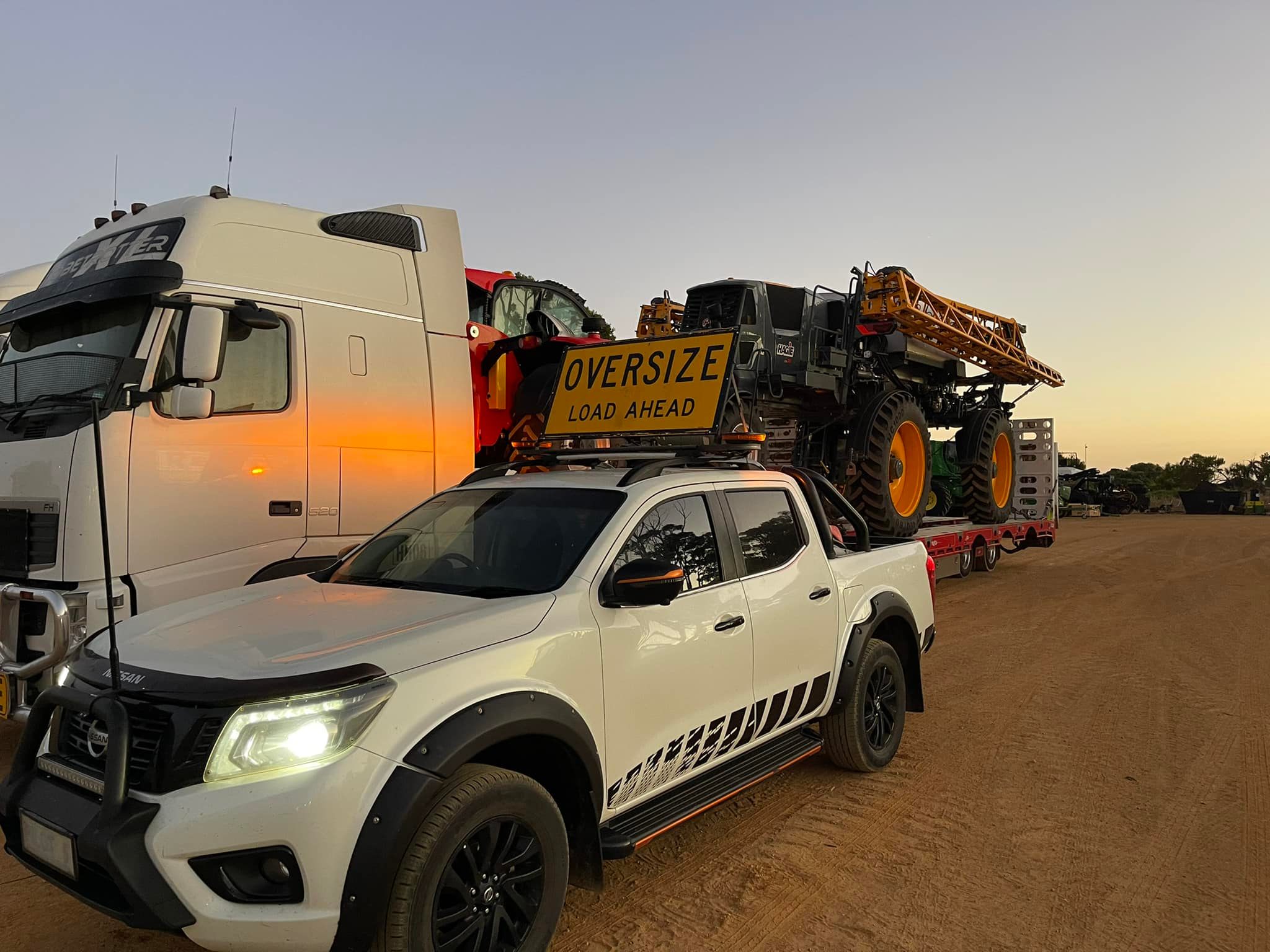 Browning Transport truck carrying a tractor with a Browning Transport pilot vehicle.