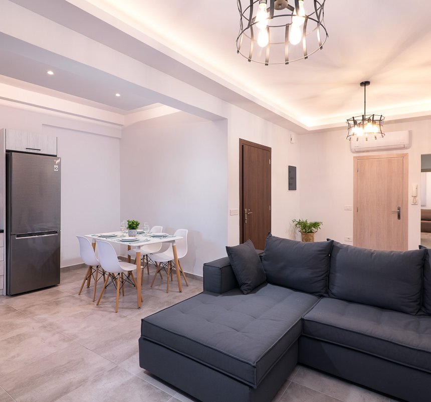 Το σαλόνι του Deluxe Apartment του Lithies Zante Living. Μεγάλος καναπές και πλήρως εξοπλισμένη κουζίνα πίσω.