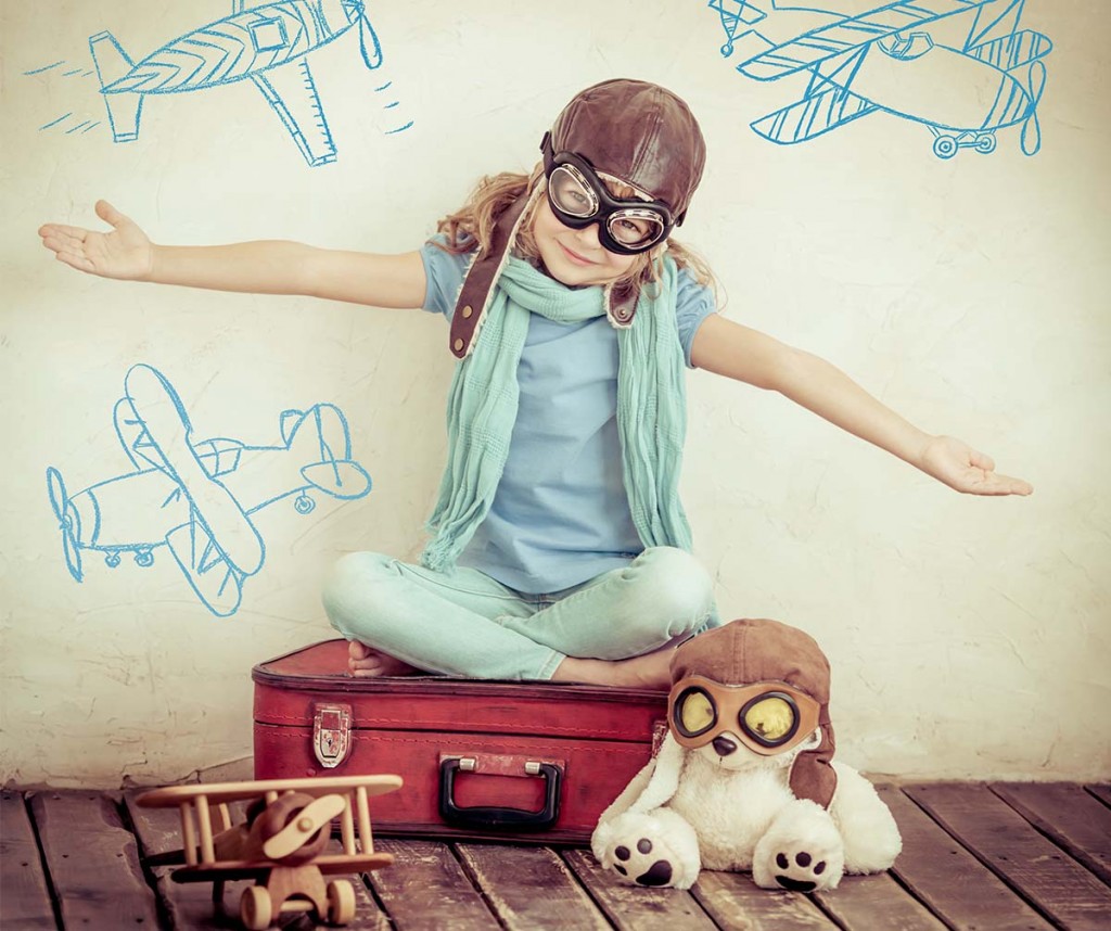 Girl sitting on suitcase wearing flight goggles