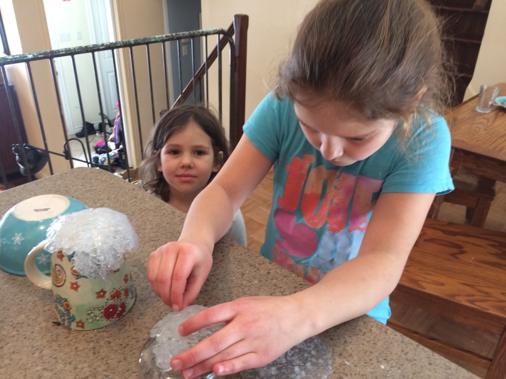 Two girls forming edible geodes over bowls