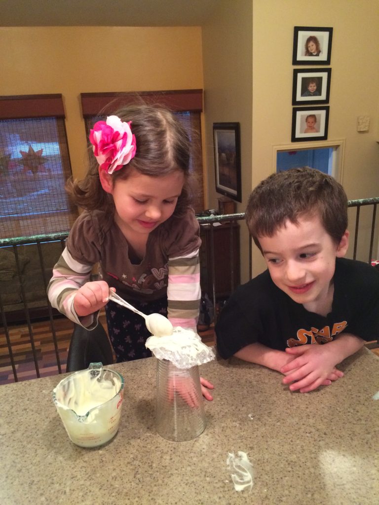 Girl and boy placing melted white chocolate chips over geodes