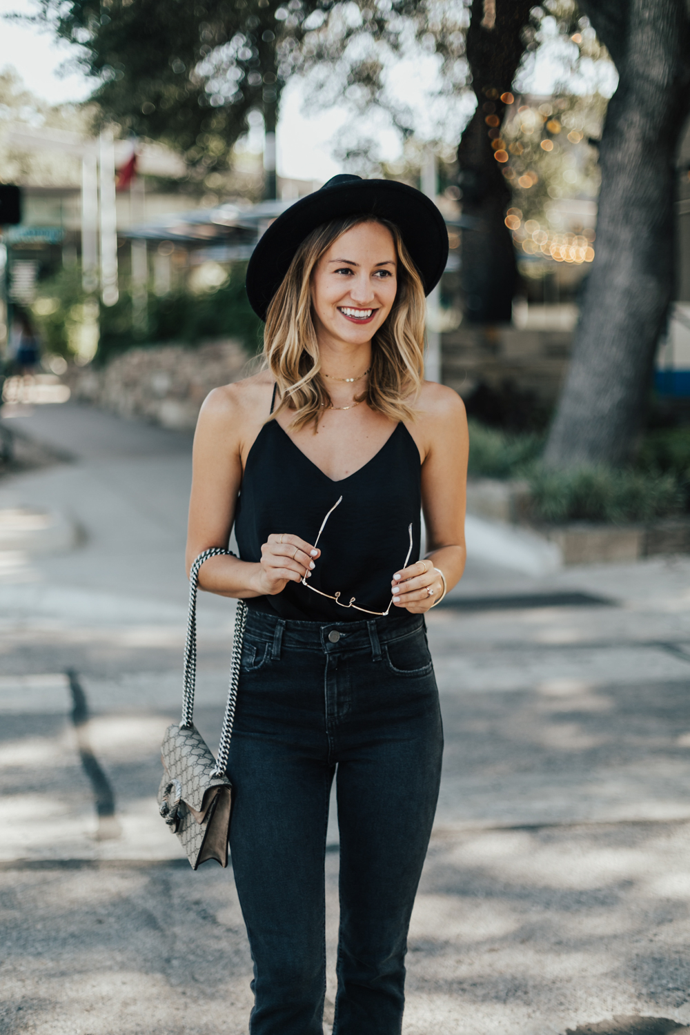 Young stylish woman wearing black cami silk top, blue cropped