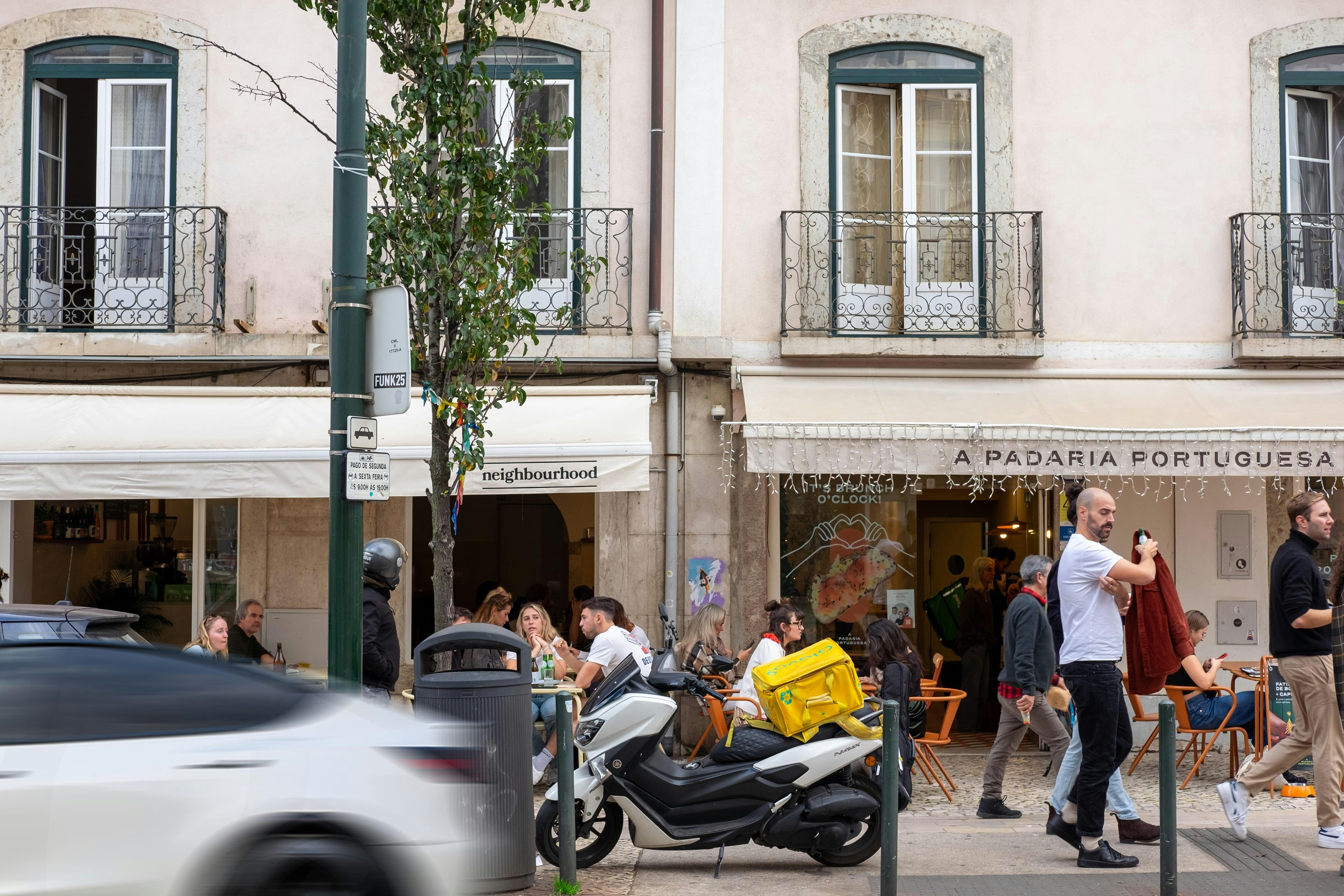 People walking and enjoying the streets of Lisbon, Portugal, with colorful buildings and lively urban atmosphere in the background.