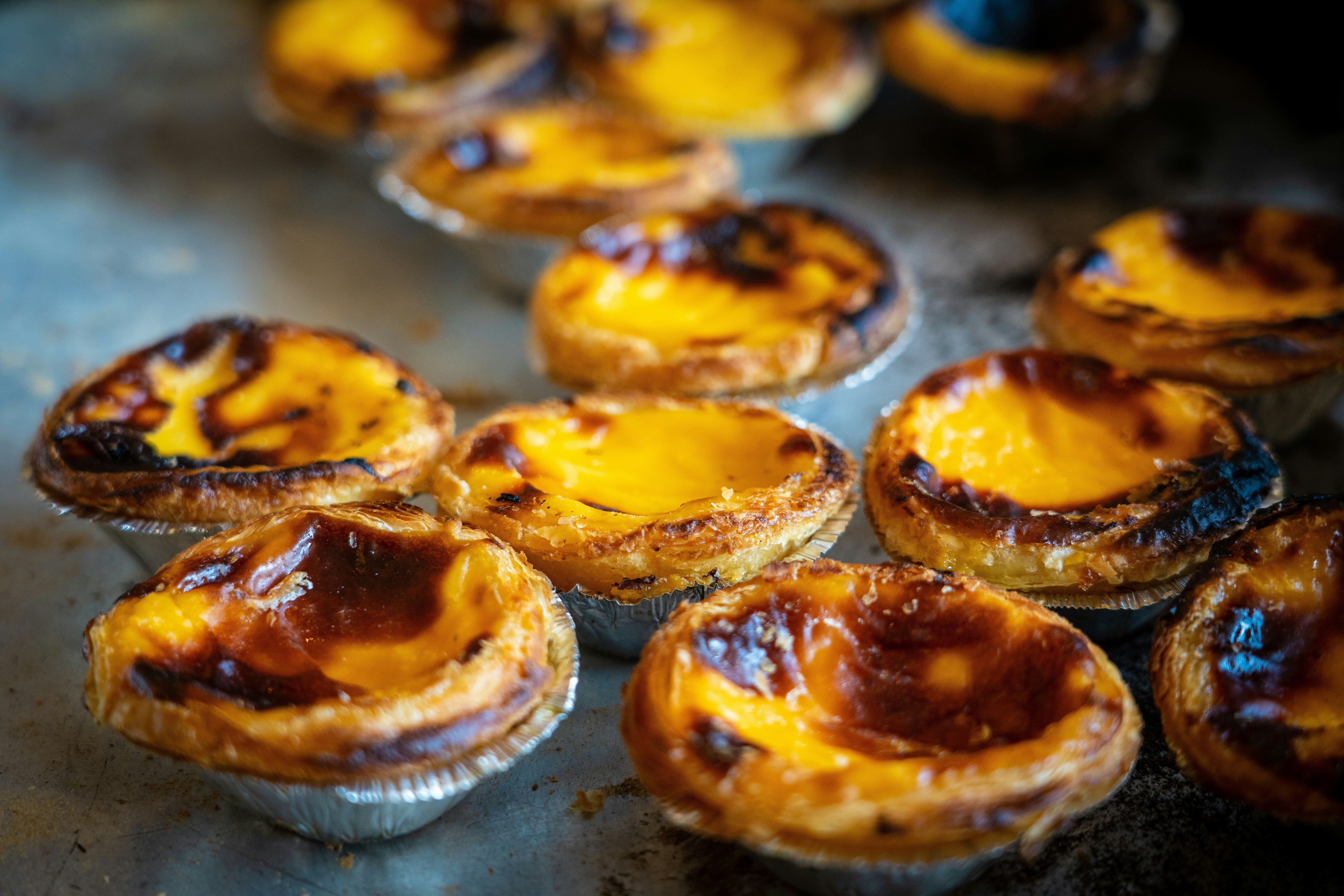 A close-up of freshly baked pastéis de nata on a plate in Lisbon, Portugal, with golden flaky crusts and creamy custard centers.