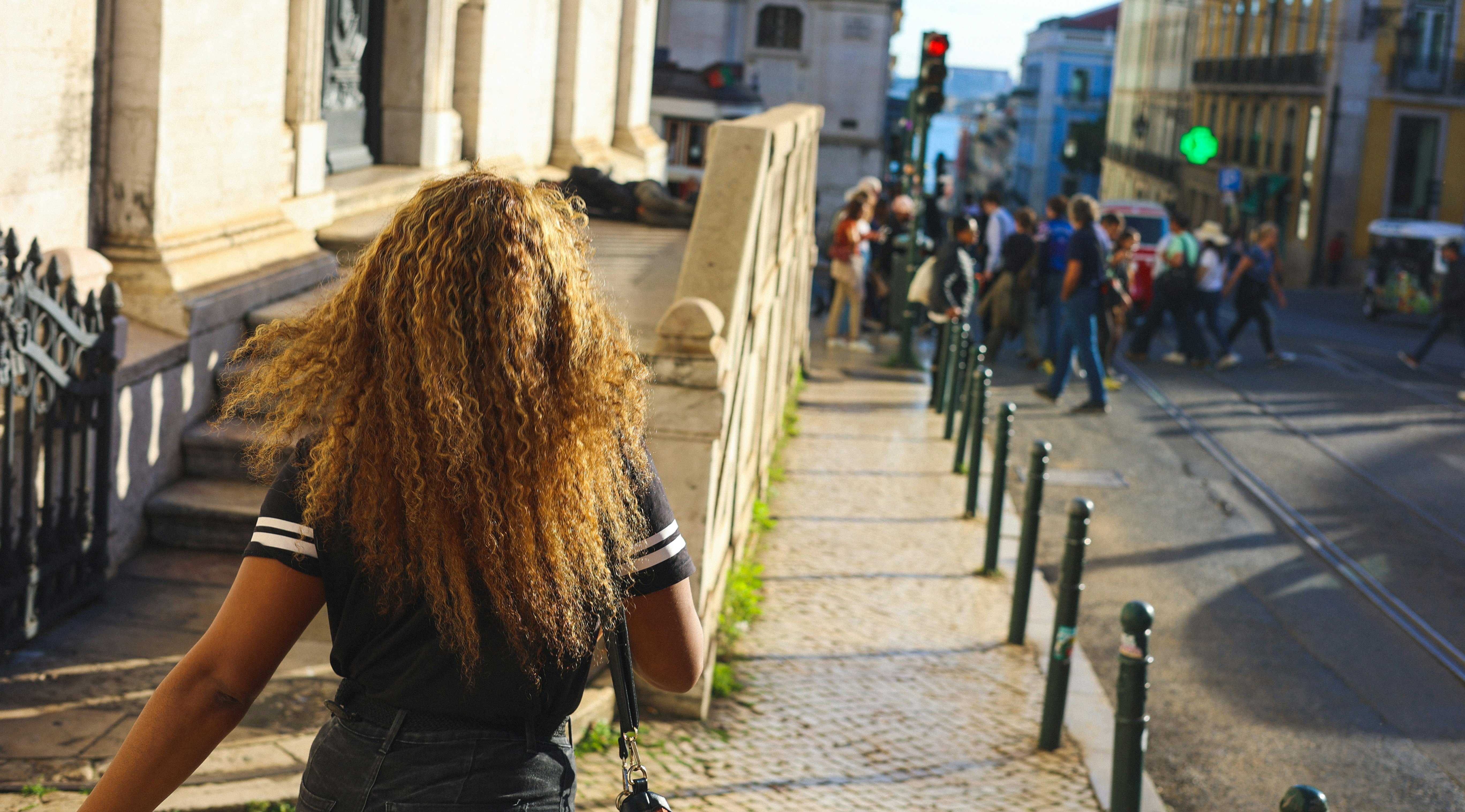 People walking and enjoying the streets of Lisbon, Portugal, with colorful buildings and lively urban atmosphere in the background.