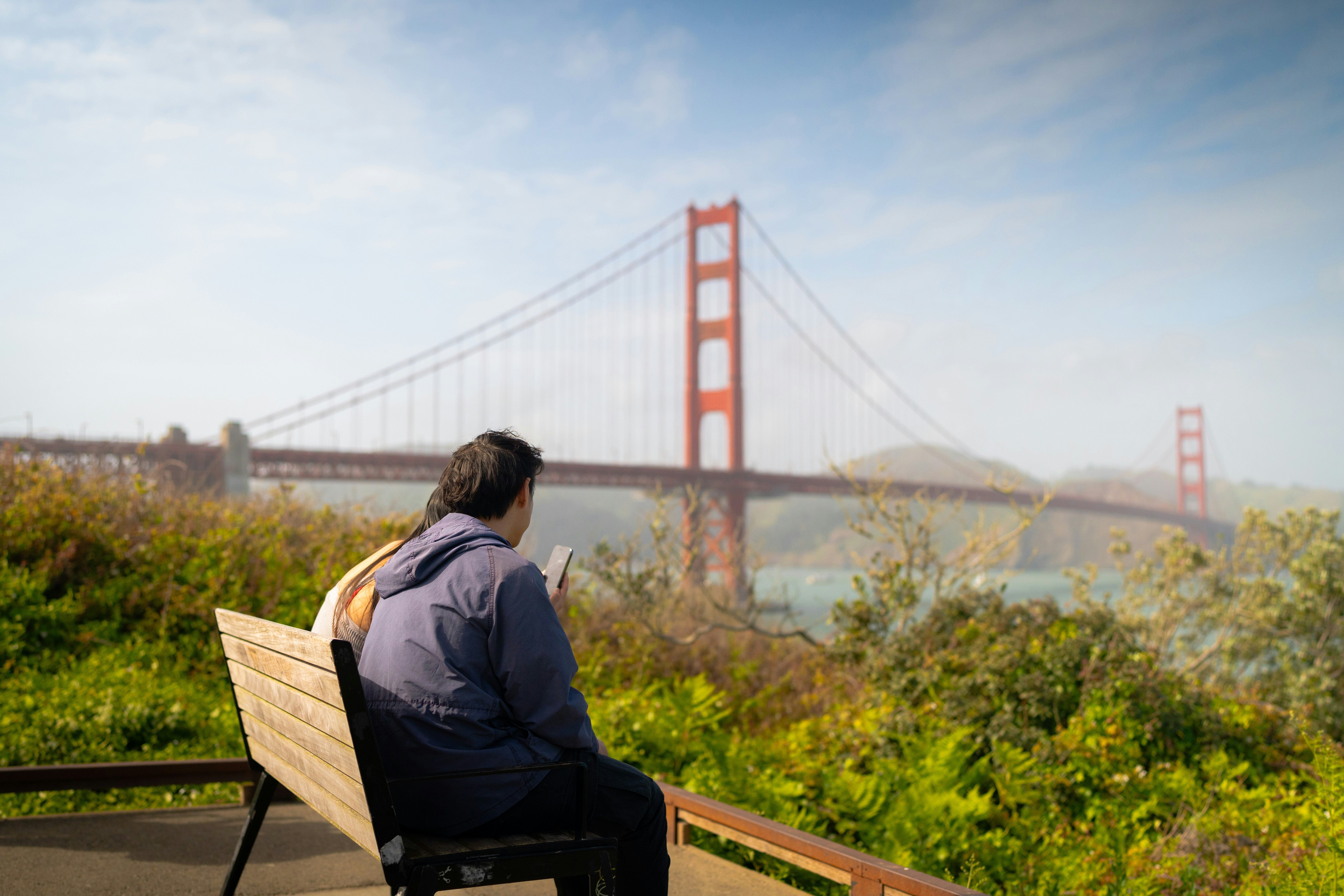 People sitting at Golden Gate Bridge Vista Point, San Francisco, CA, USA