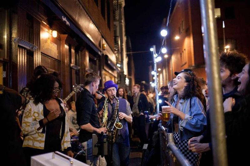 Programmation musicale d'été : un groupe de musique composé d’un duo de saxophonistes fait un concert devant un bar.