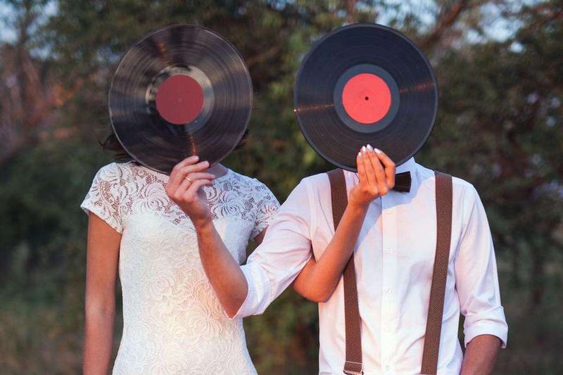 Couple de jeunes mariés cachant leurs visages avec un vinyle.