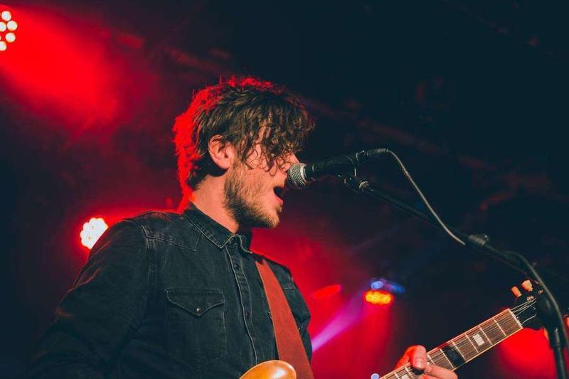 Chanteur guitariste dans un concert pour les musiciens avec de la lumiére rouge