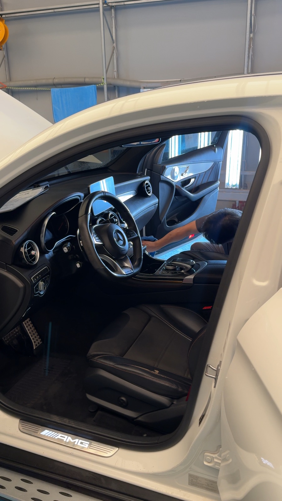 The front cabin of a secured white Mercedes-AMG being wiped down at the LMN facility.