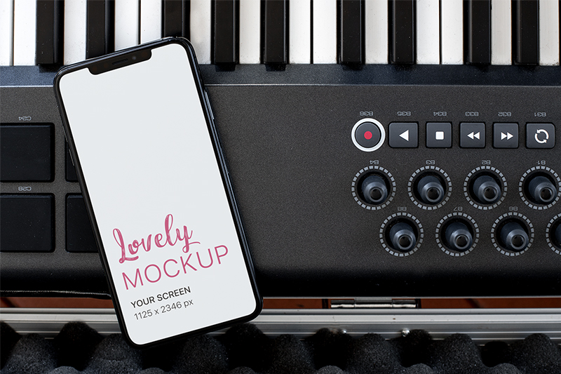 Download iPhone Mockup Lying over a Musical Keyboard - Lovely Mockups