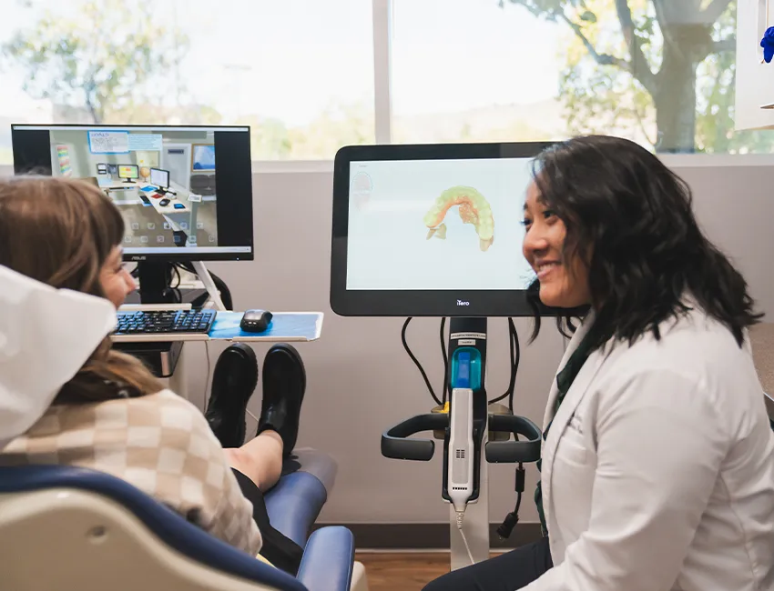 Happy patient and dentist next to modern iTero dental technology
