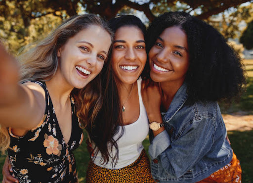 Joyful excited close group of diverse friends smiling for selfie outdoors in a park