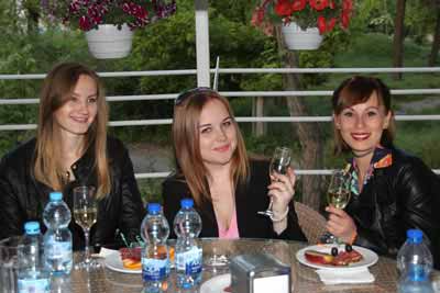 A photo of three beautiful foreign women at a table, each enjoying a glass of champagne.